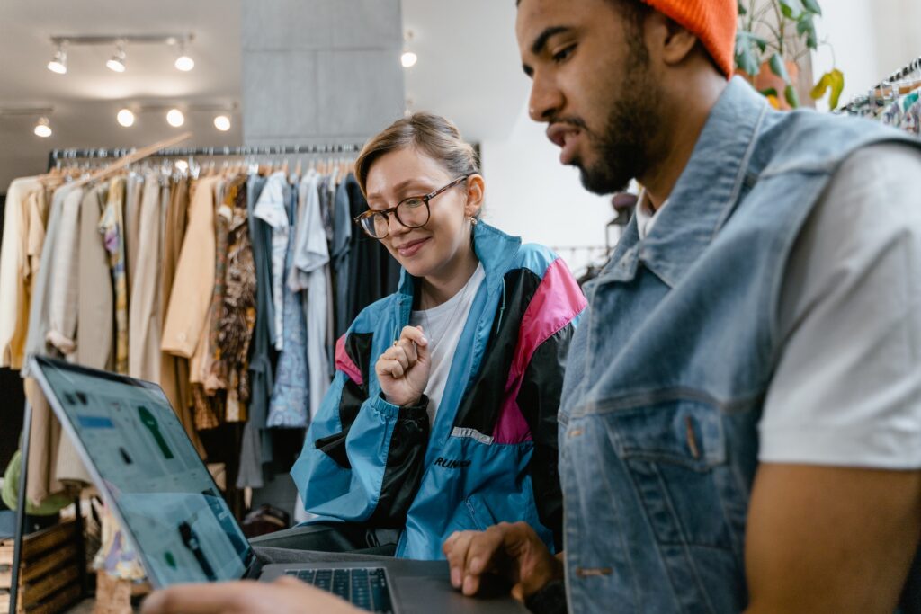 Emprendedores de tienda de ropa con computadora configurando tienda en línea en Shopify.