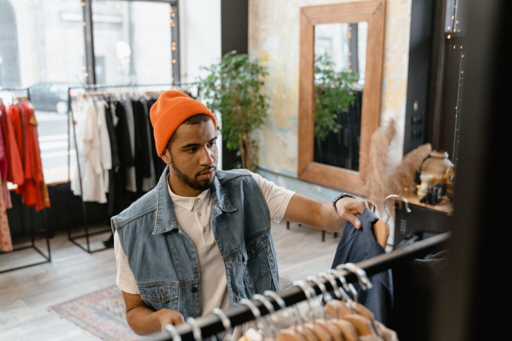 Emprendedor dueño de tienda de ropa organizando ropa por colecciones en Shopify.